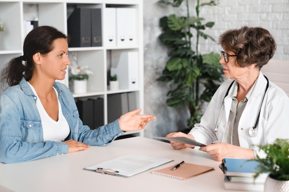 Woman discussing hormonal imbalance symptoms with a doctor during a consultation.